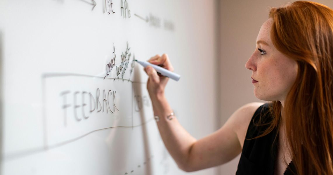 Woman writing her opinion on a whiteboard above the word feedback