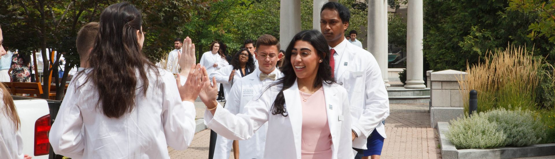 two students high five in their white coats